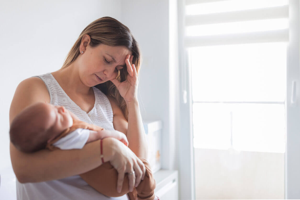 Woman with post partum depression while putting newborn baby to sleep.